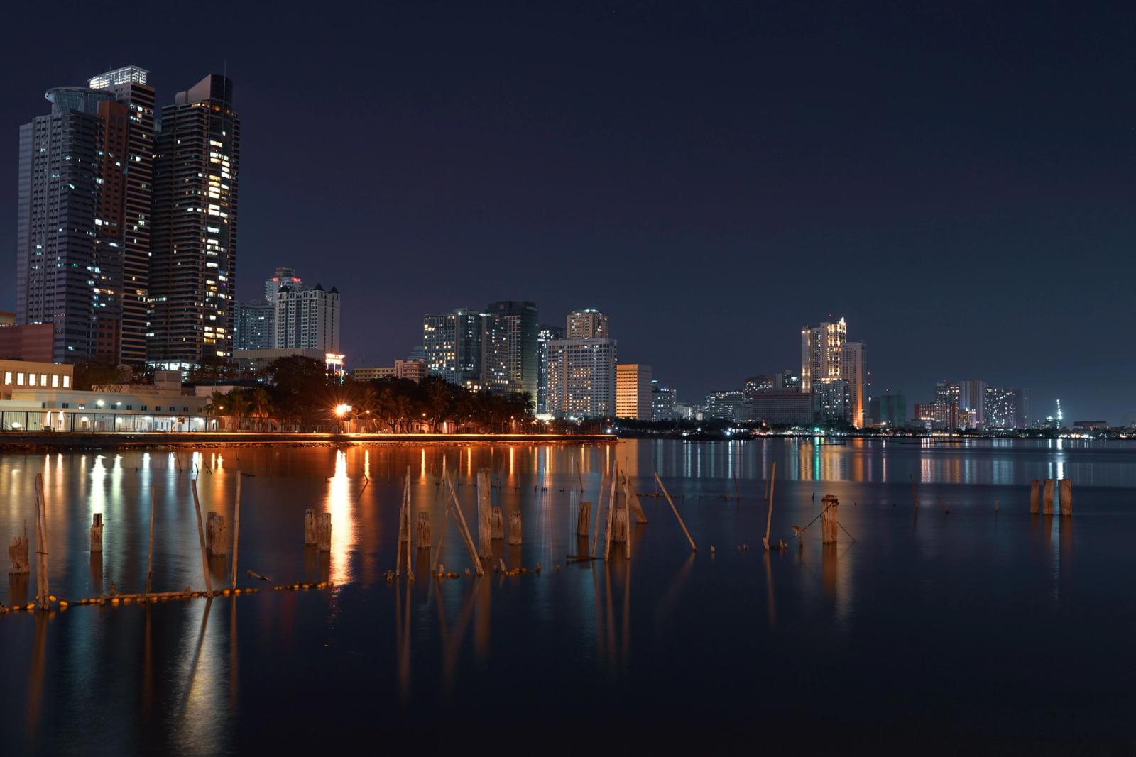 Illuminated skyscrapers reflected on the waterfront in Manila cityscape at night