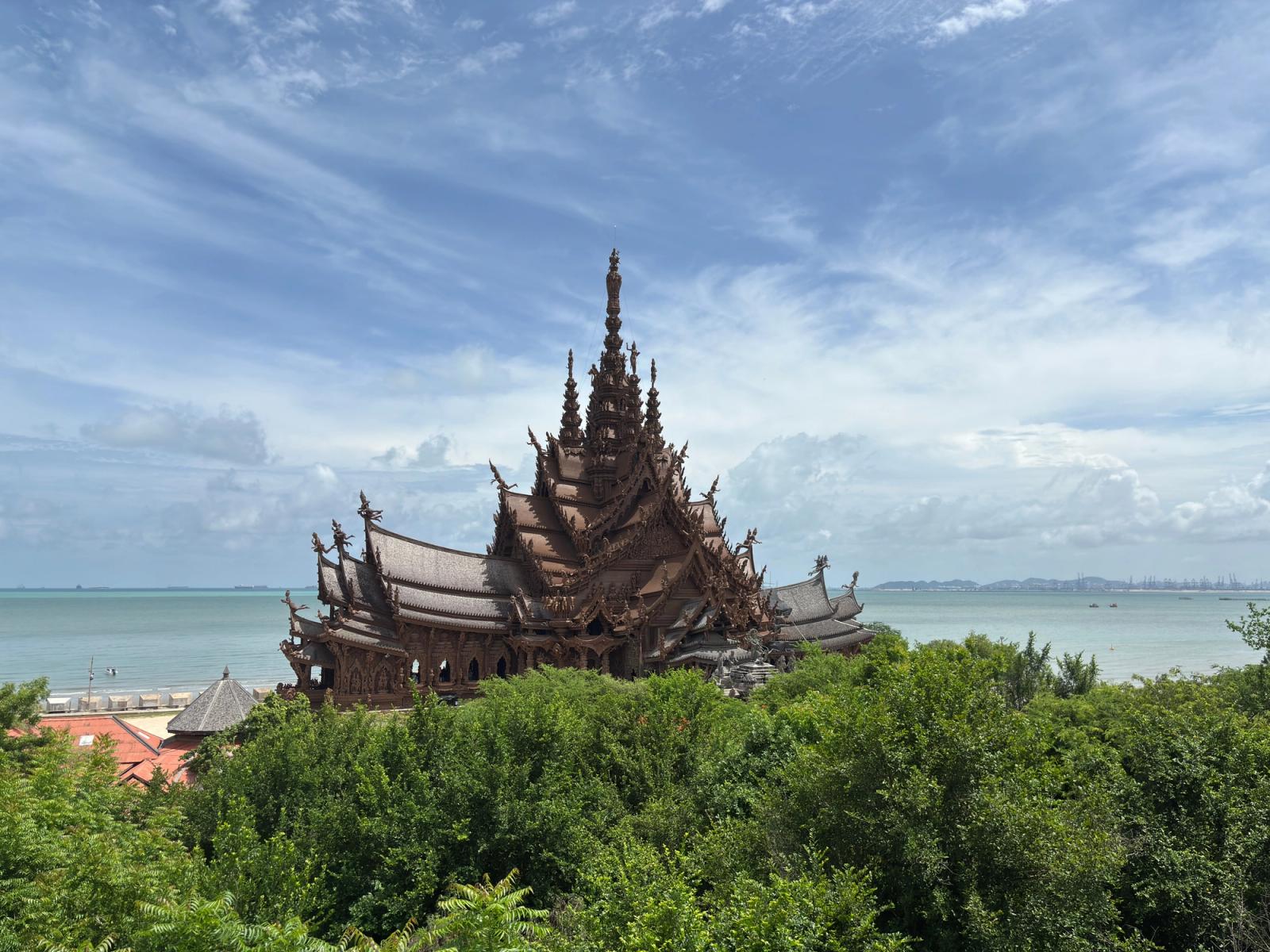Ornate wooden sanctuary spire rising above dense greenery beside the sea