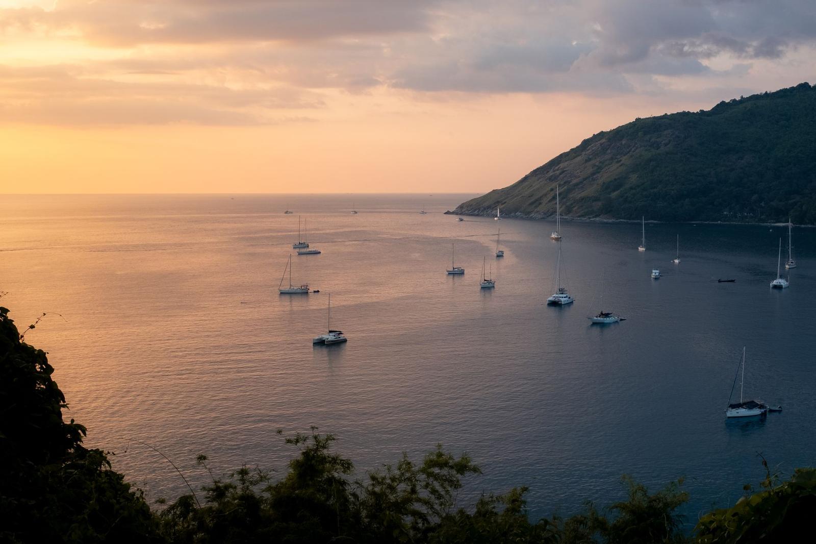 Sailboats anchored in a calm bay lit by a golden sunset