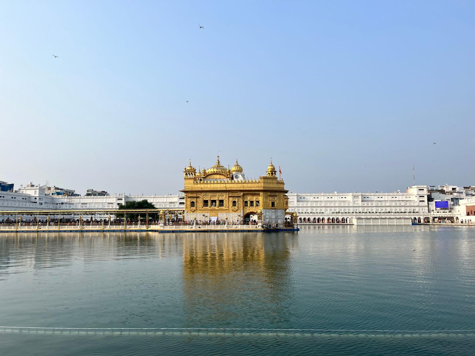 A golden temple mirrored in a calm lake beneath a pale sky