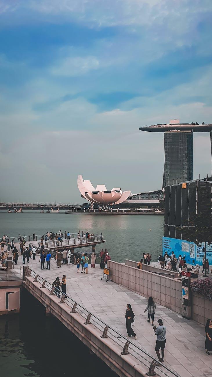 Waterfront promenade with visitors walking past a lotus-shaped museum