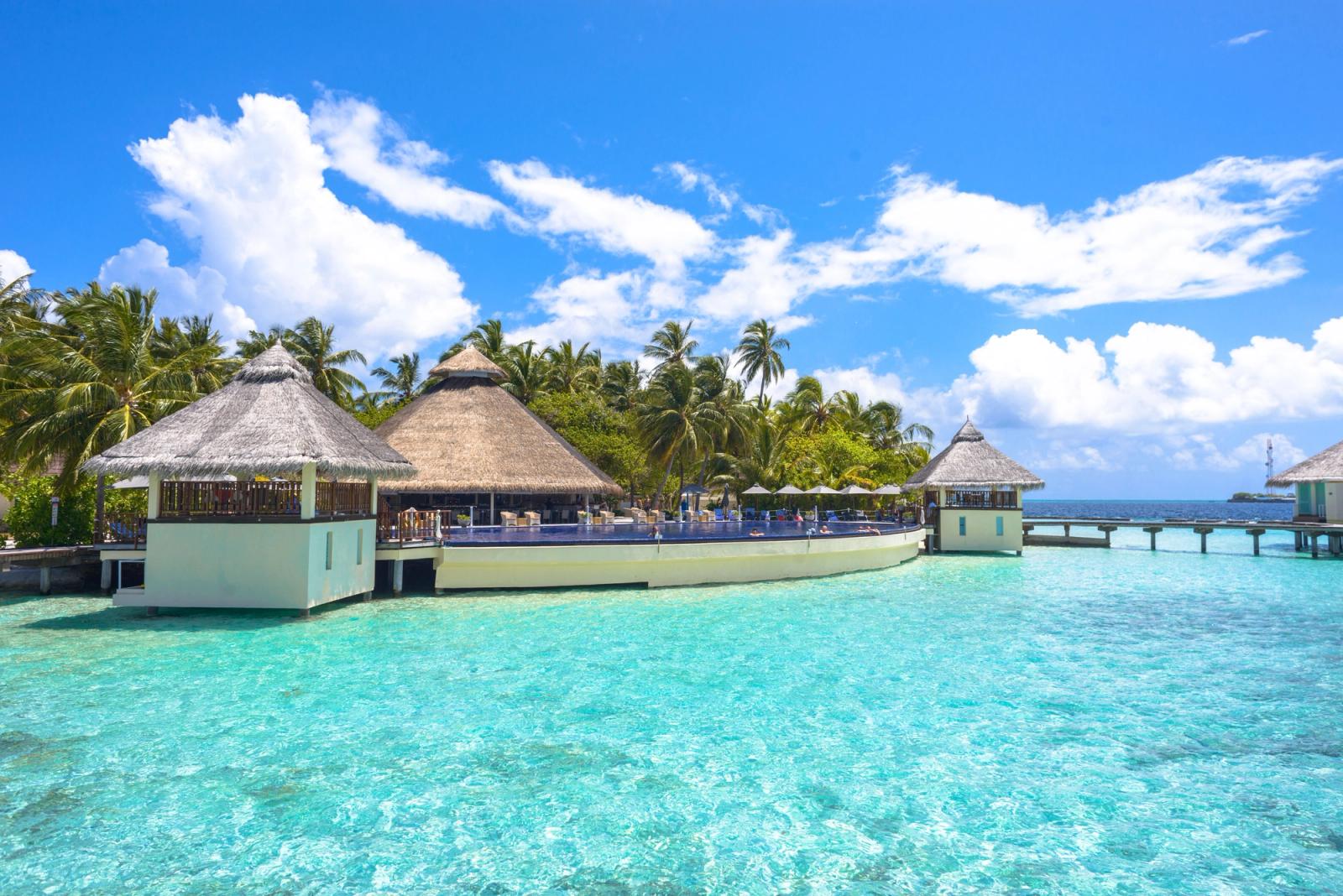 A thatched overwater pavilion surrounded by turquoise lagoon water