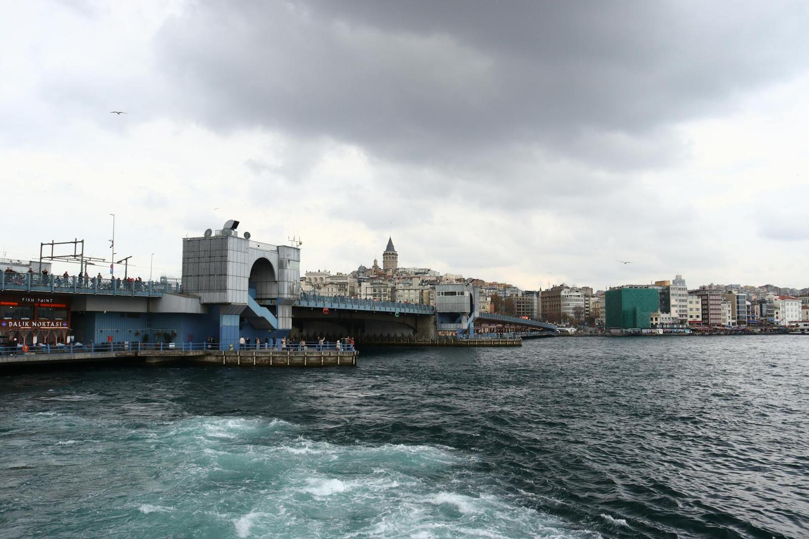 View from a boat of a historic tower and bridge on a cloudy day