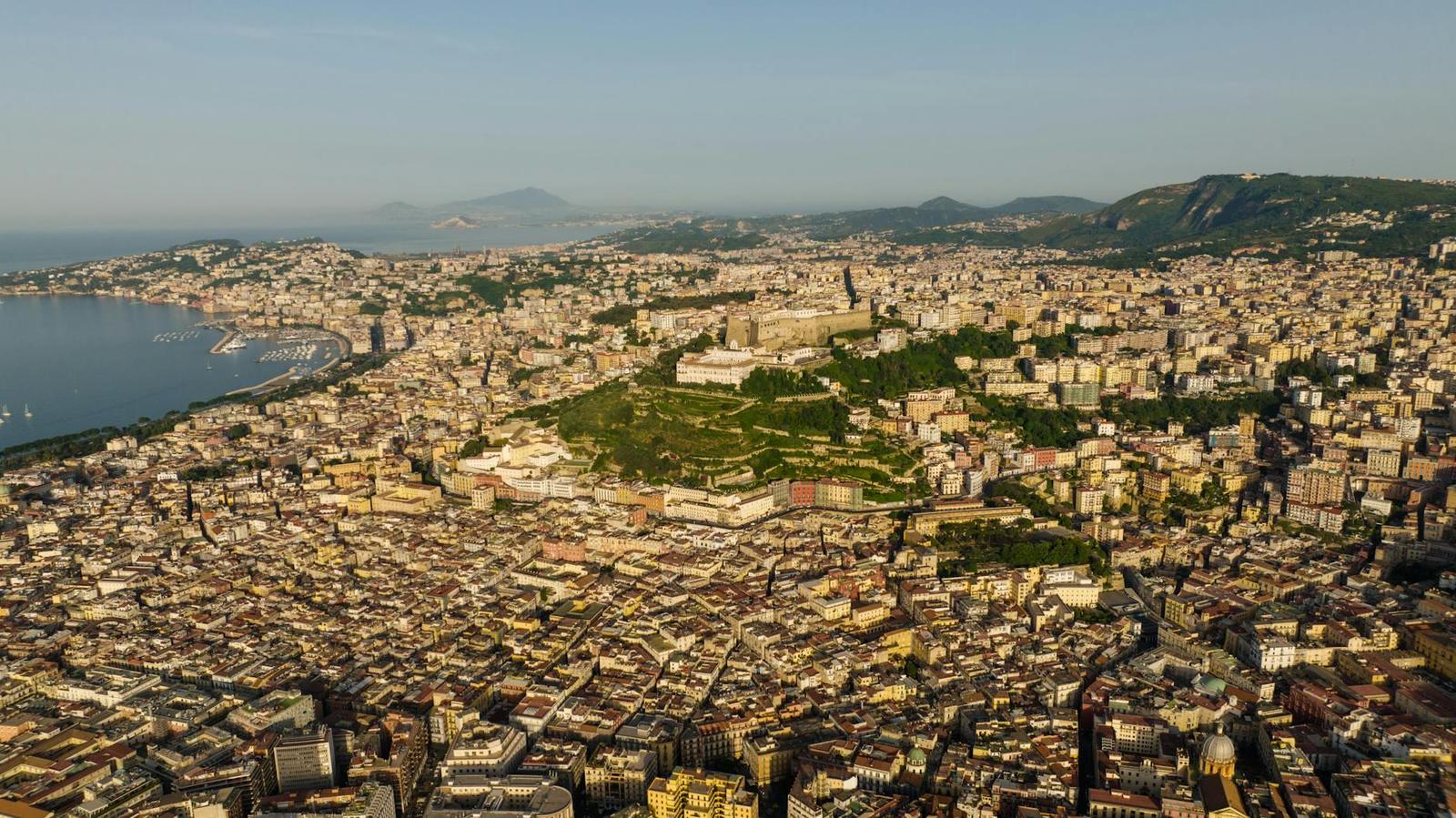 Aerial view of a dense coastal city spreading toward distant hills