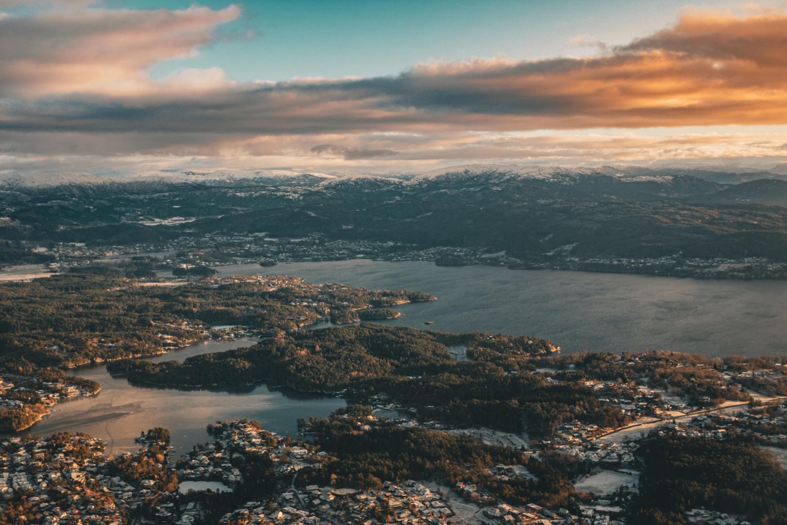 Aerial view of a fjord town and snow-dusted hills at golden hour
