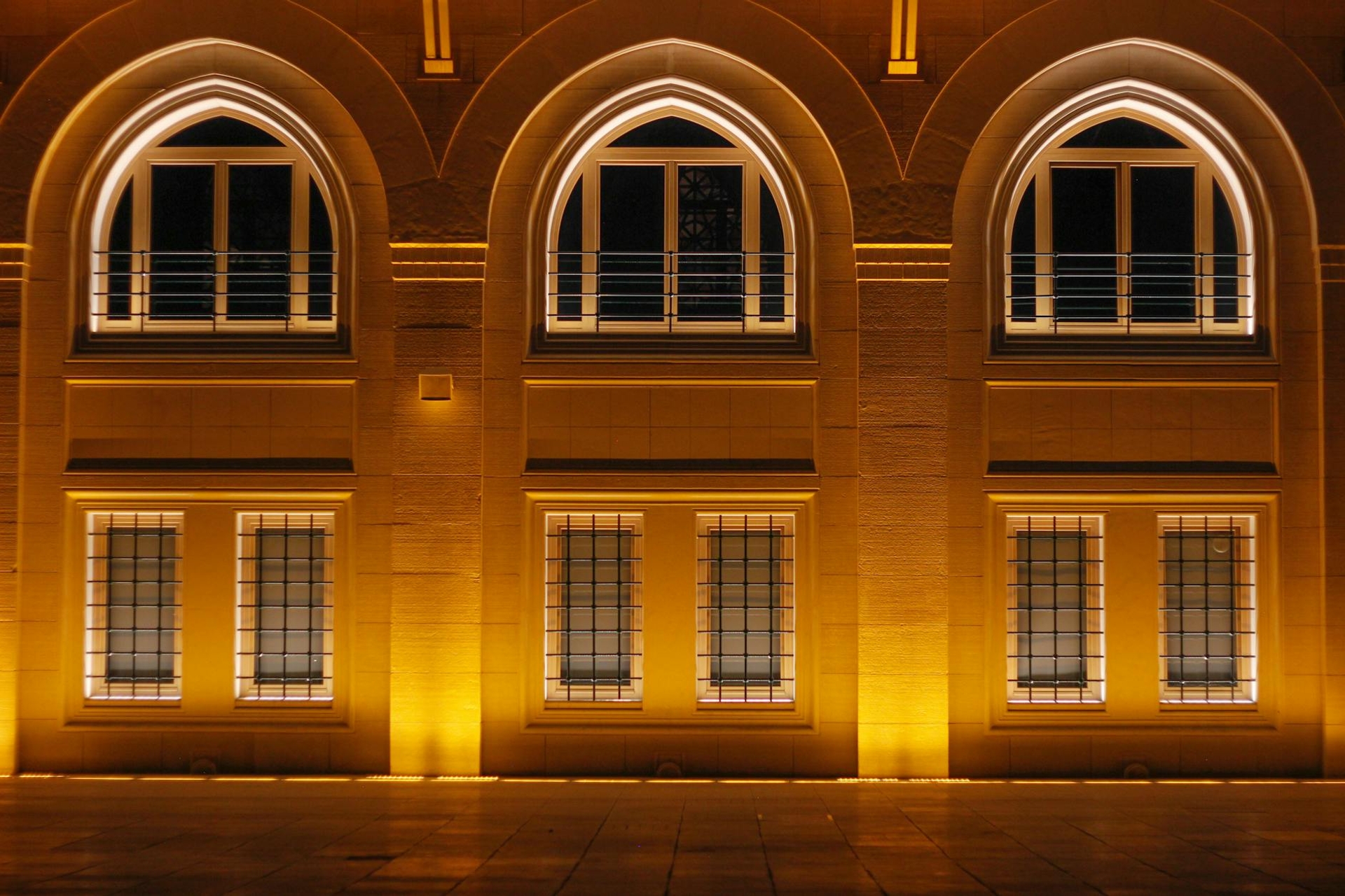 Illuminated arched windows on a stone facade at night