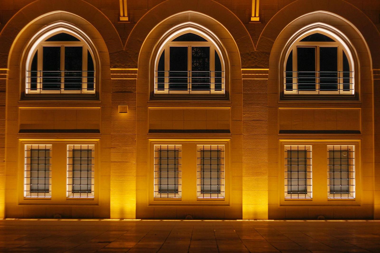 Illuminated arched windows on a stone facade at night