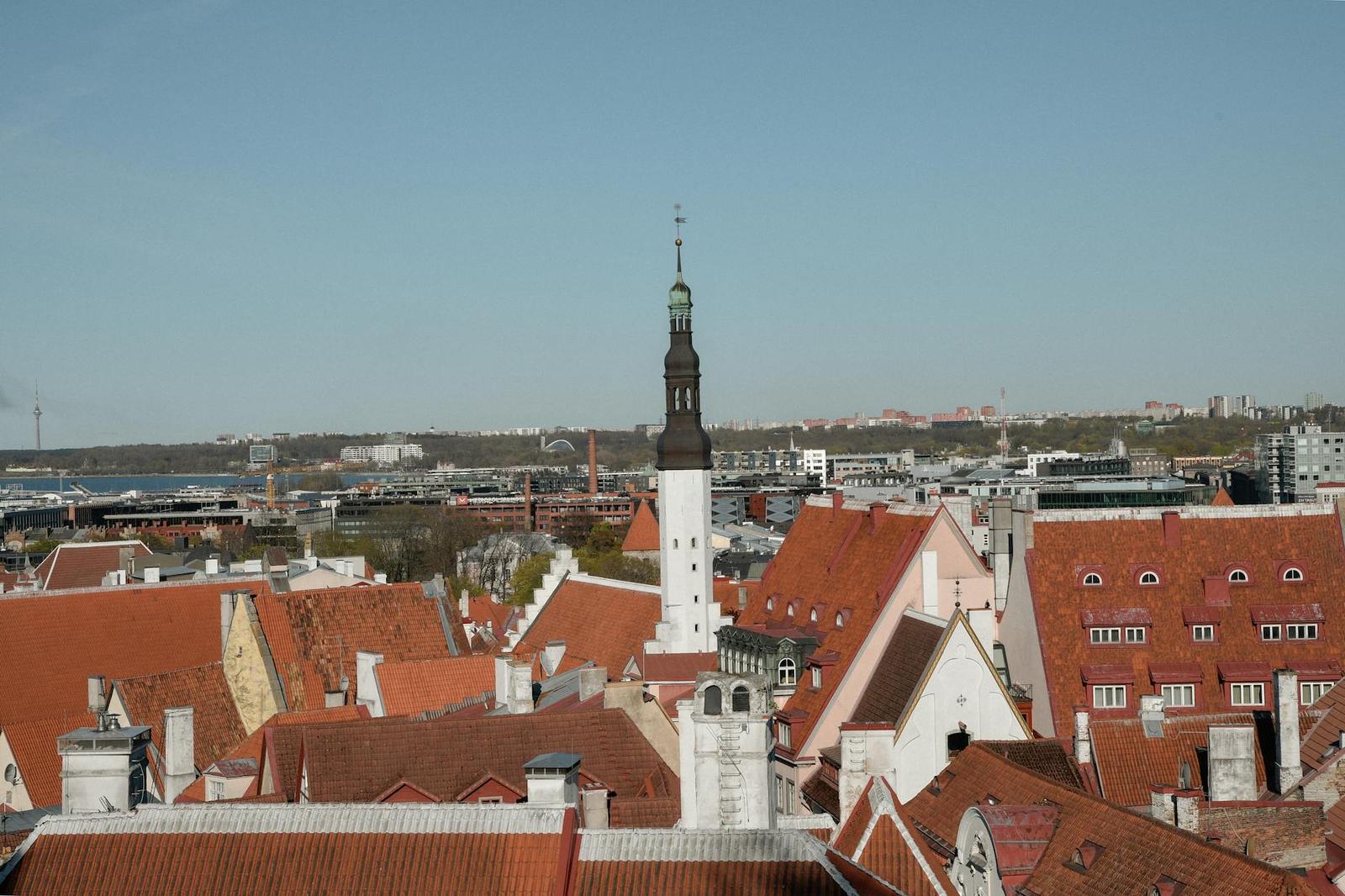 A tall church spire rising above a cluster of red-tiled old-town rooftops