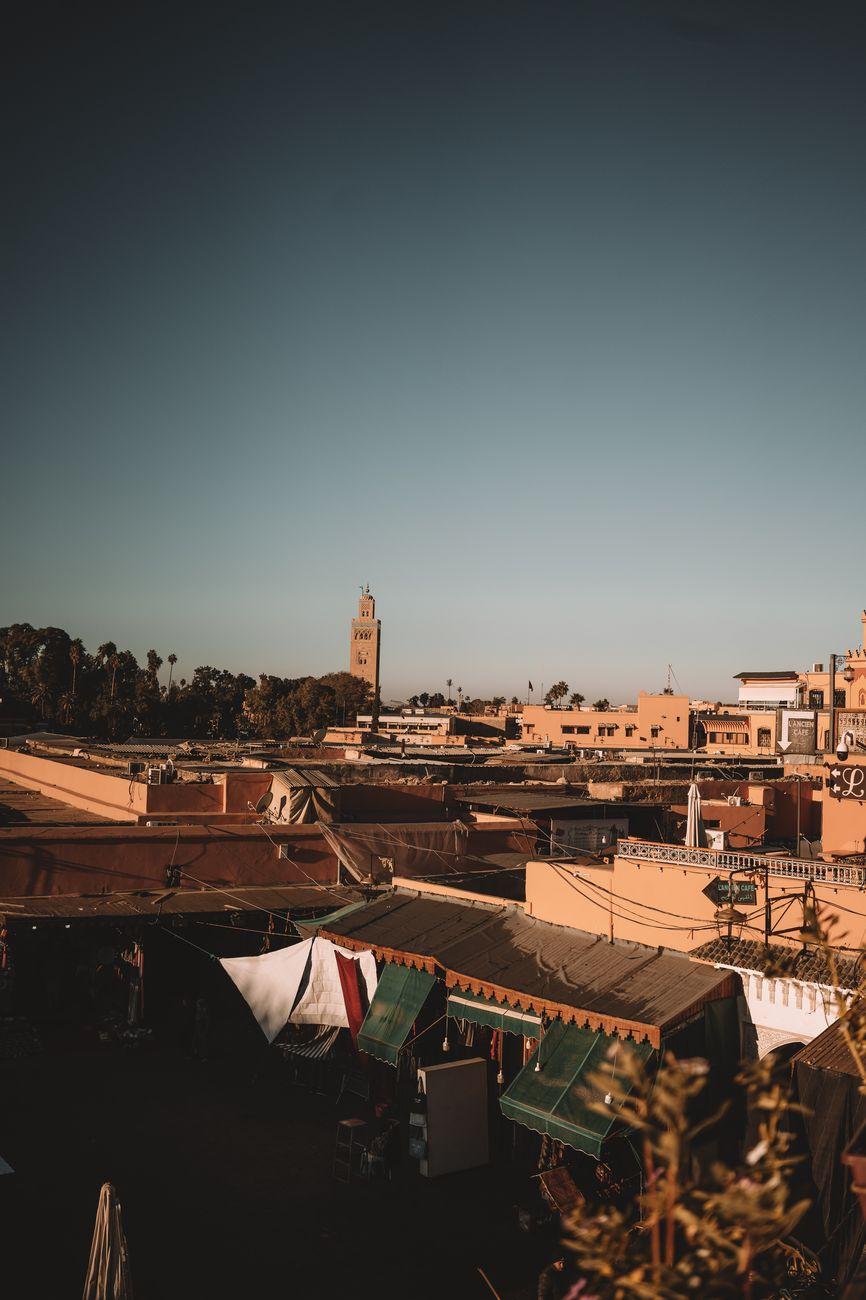 Rooftop view over a sandy-walled old town with a tall minaret at dusk