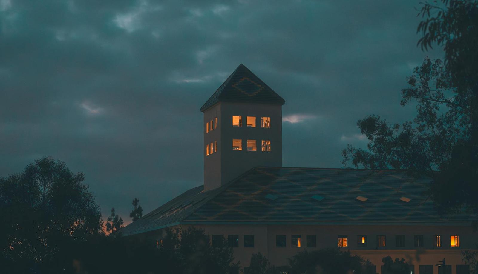 A lodge with a lit tower silhouetted against a dusky sky