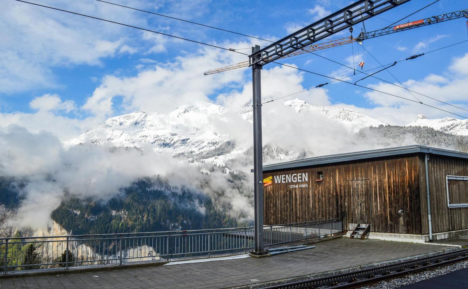 Wooden alpine train station platform with cloud-wrapped mountains behind