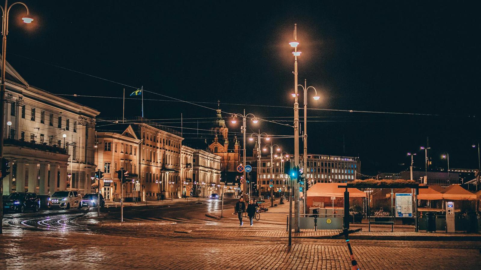 A lamplit cobblestone square with pedestrians on a winter night