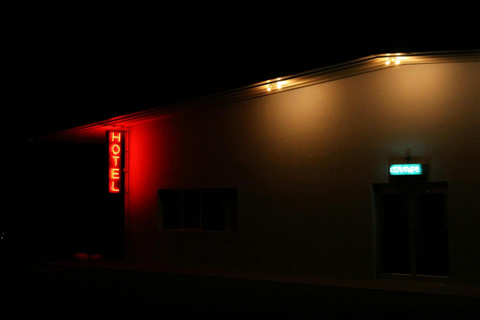 A red neon HOTEL sign glowing on a dark roadside building at night