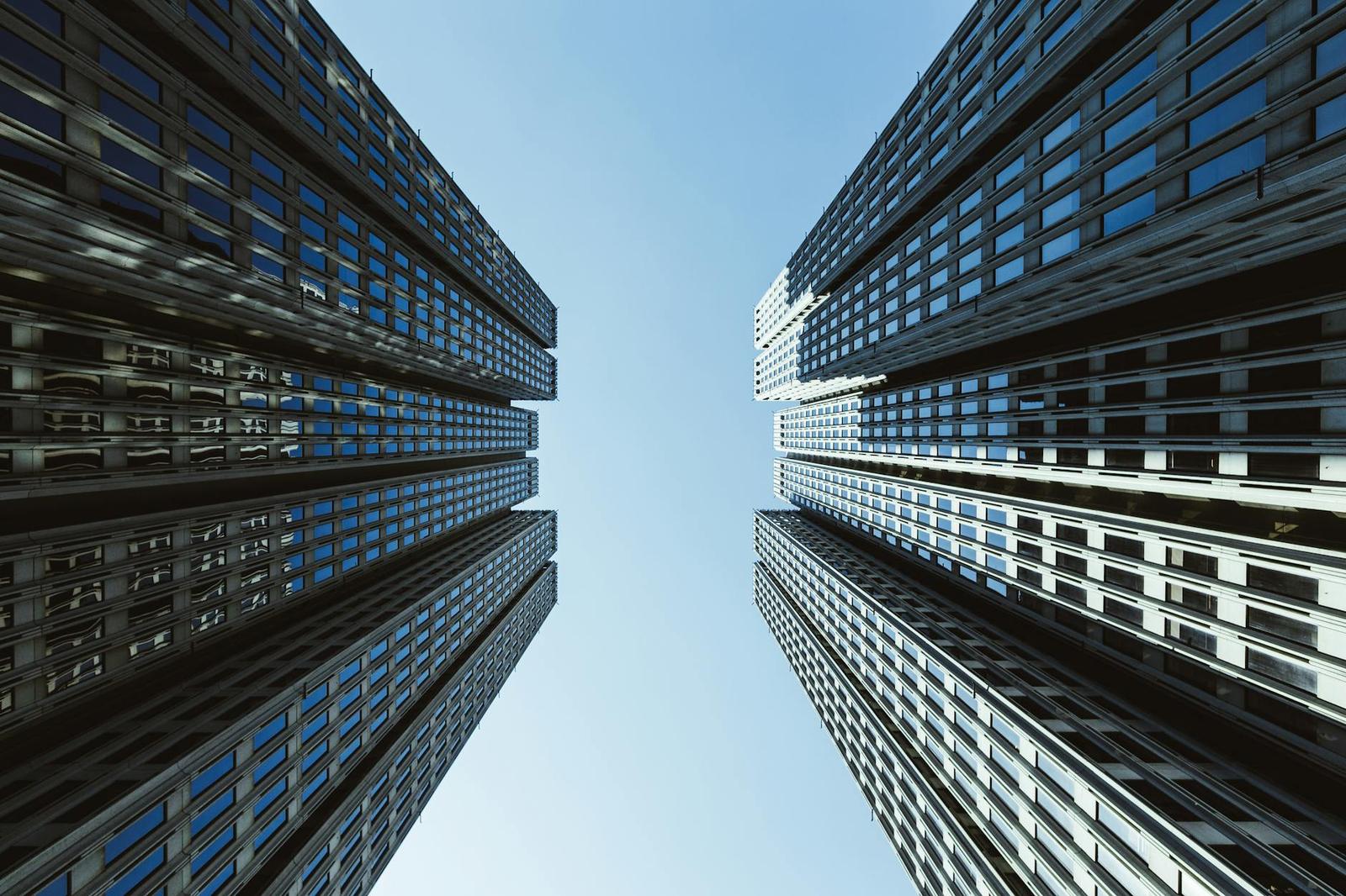 Looking up at facing glass office towers against a clear sky
