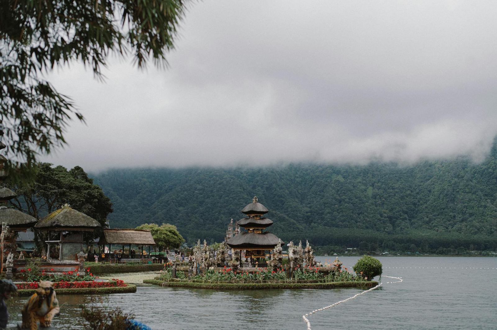 A tiered lakeside temple sits on a small island beneath cloud-covered hills