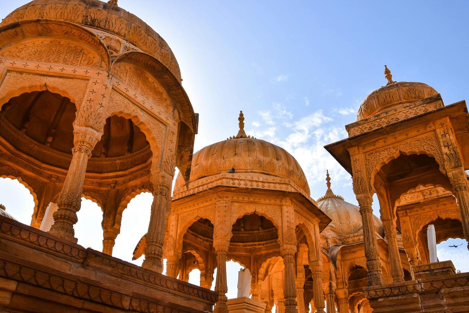 Ornate sandstone cenotaph domes silhouetted against a blue sky