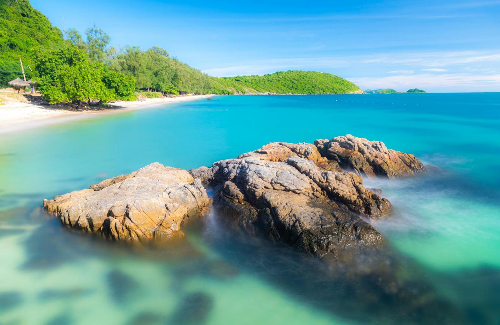 Weathered boulders rising from a turquoise cove edged by forest