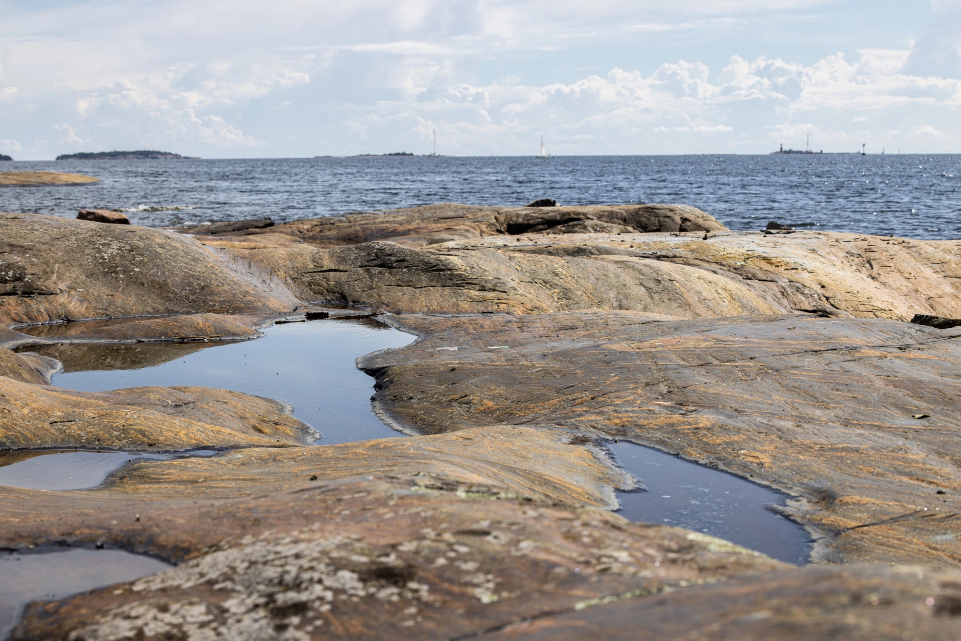 Scenic view of a rocky coastline in Helsinki with distant islands in the background