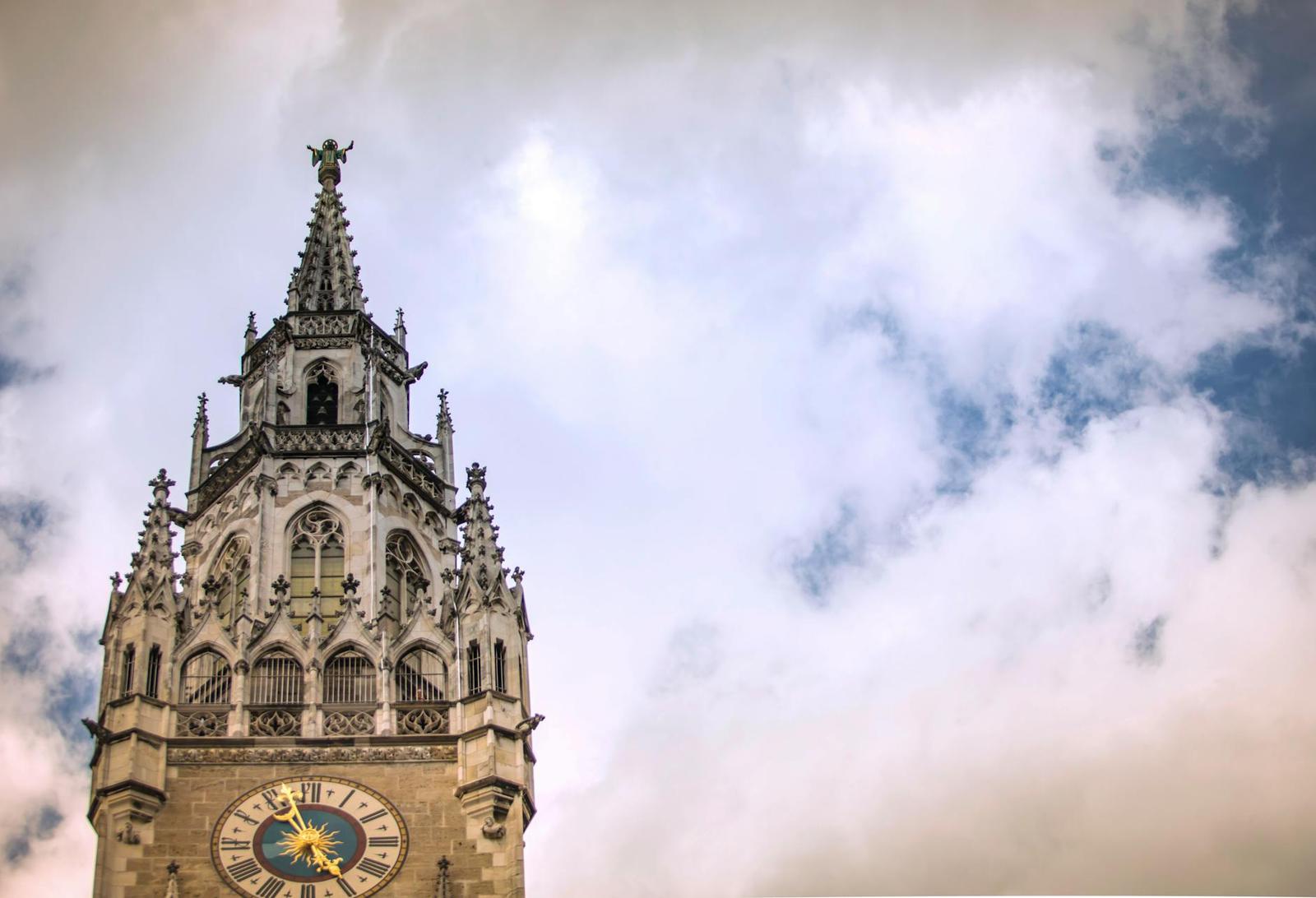A majestic gothic clock tower in Munich with dramatic clouds in the background