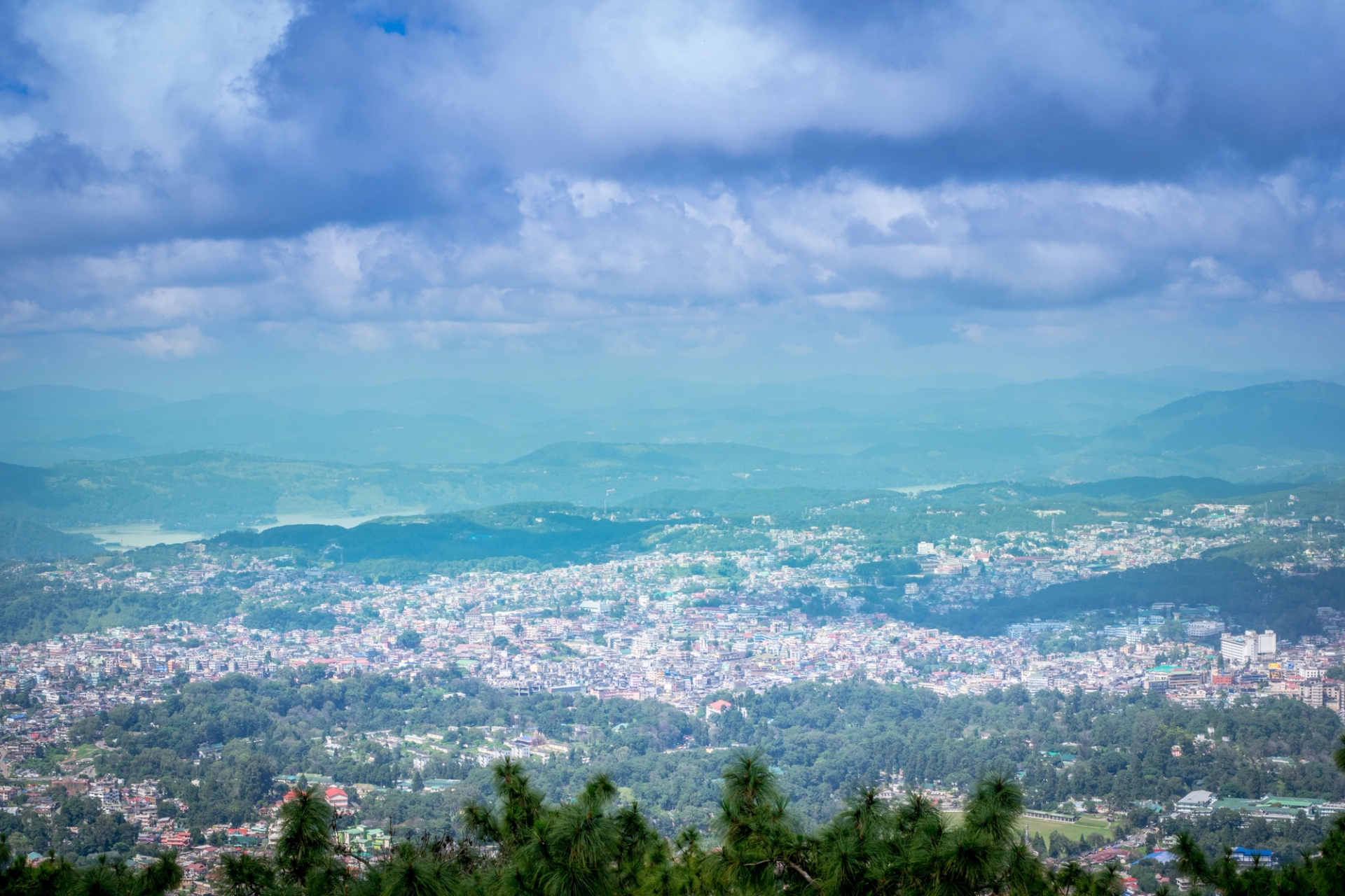 Breathtaking aerial view of a vibrant town in West Khasi Hills, India surrounded by lush greenery and mountains under a vivid sky