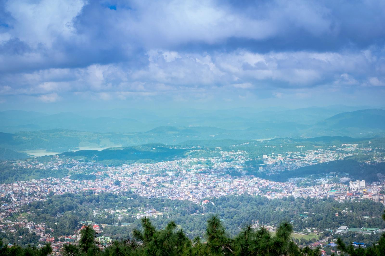 Breathtaking aerial view of a vibrant town in West Khasi Hills, India surrounded by lush greenery and mountains under a vivid sky