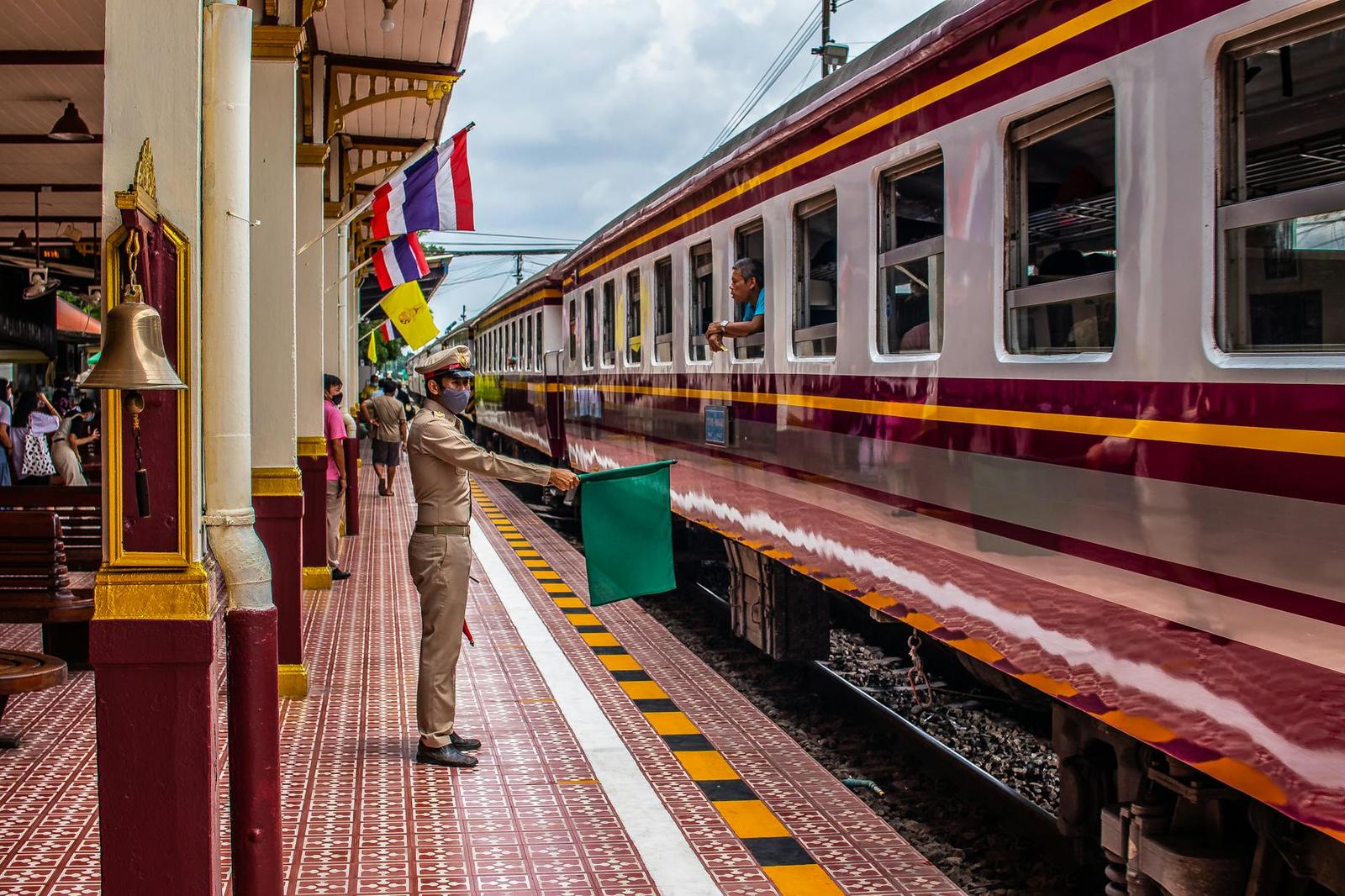 A uniformed station officer holding a flag beside a stopped train