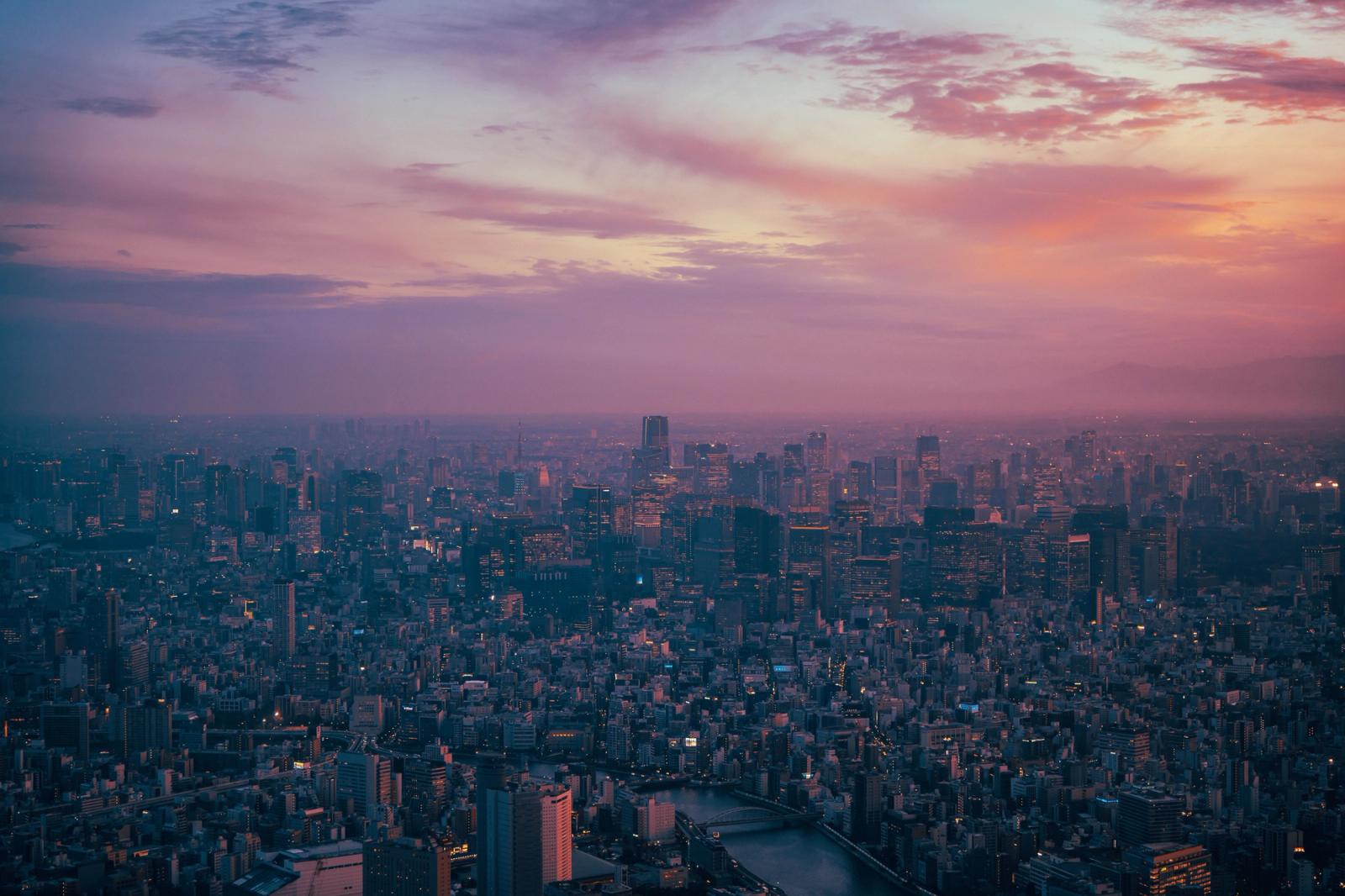 A breathtaking aerial view of Tokyo's skyline at twilight showcasing vibrant neon lights and a serene sunset