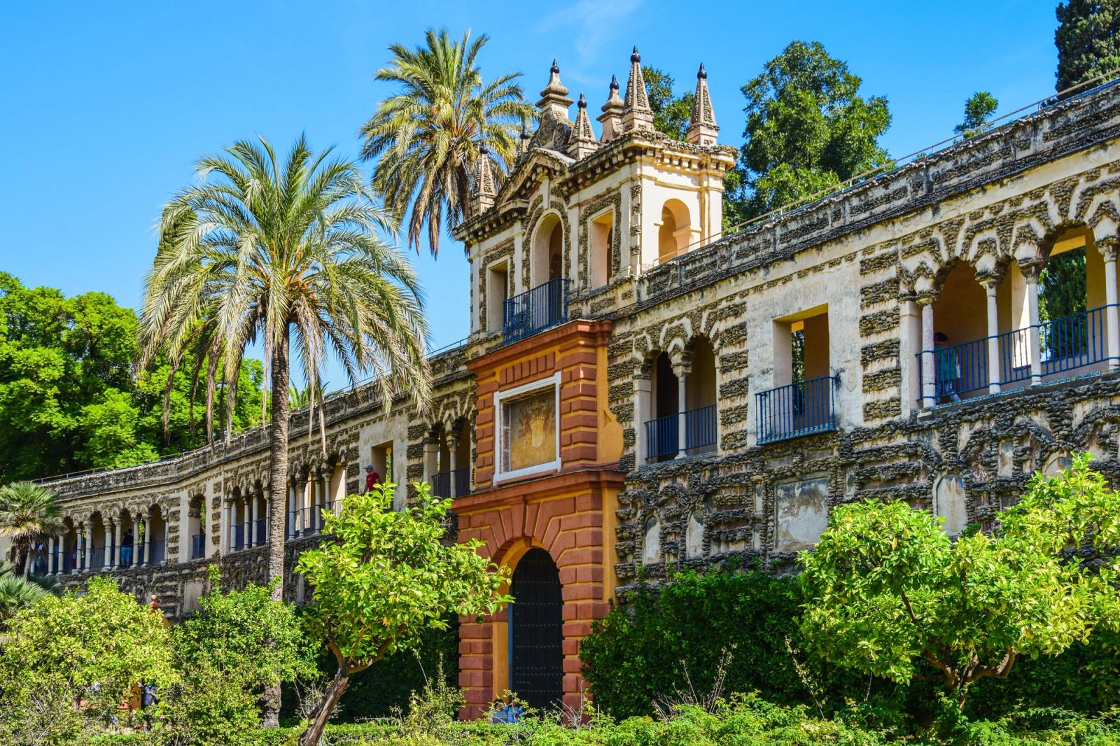 Discover the stunning Alcazar Palace with lush gardens, palm trees, and historic architecture in Seville, Spain