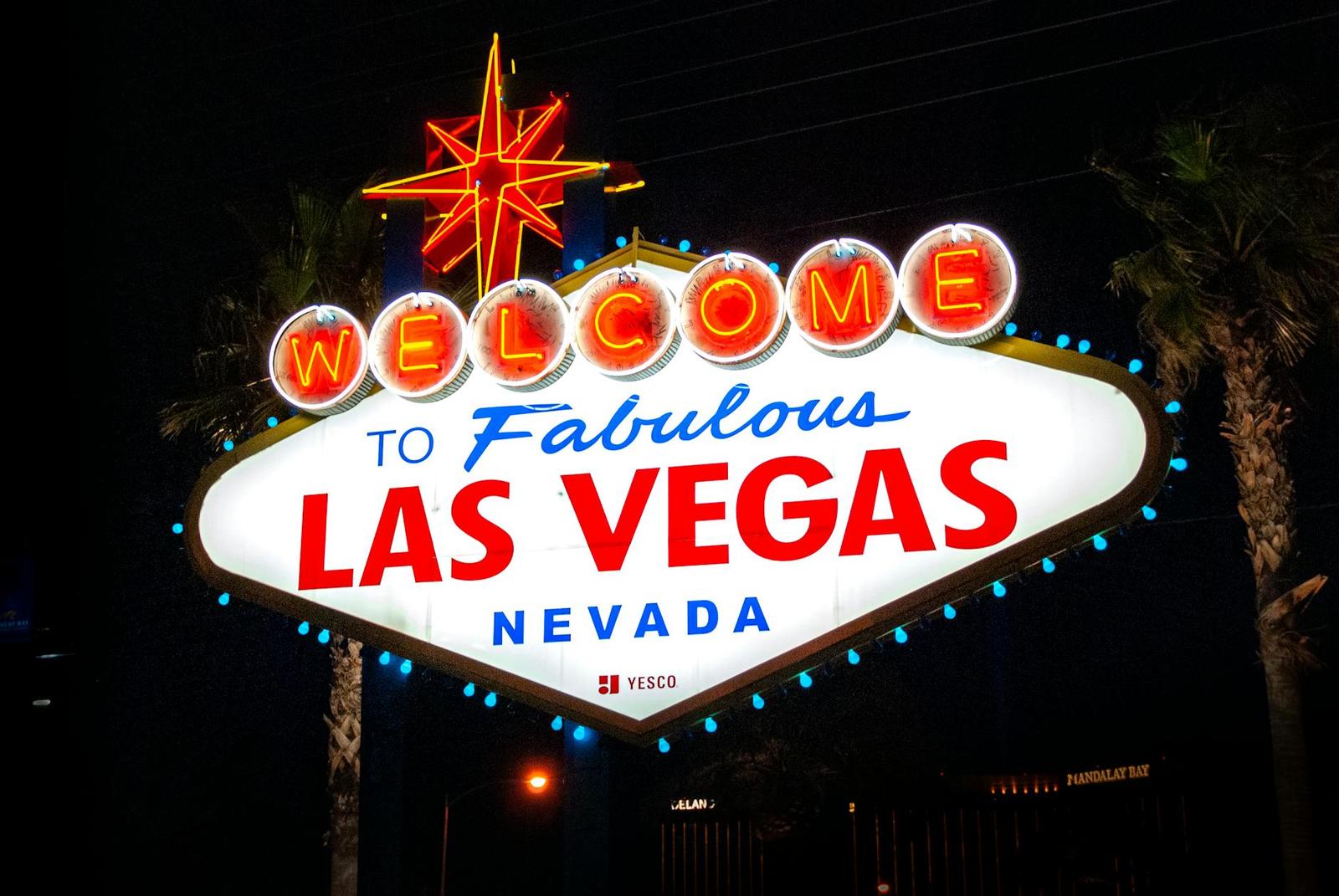 An illuminated welcome to Las Vegas sign glowing red and blue at night