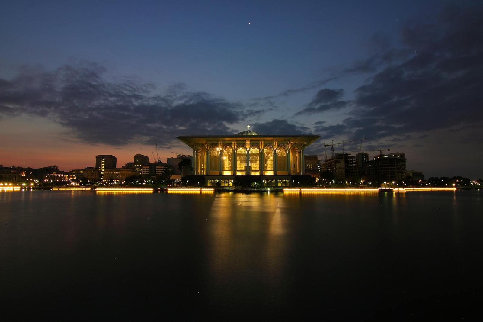 A golden domed waterfront building illuminated against a dusk sky