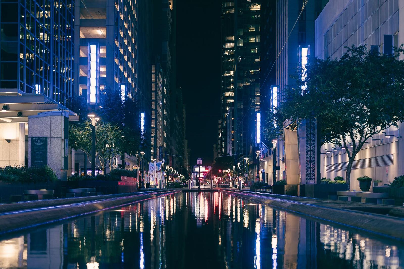 City canal reflecting illuminated skyscrapers and neon signage at night