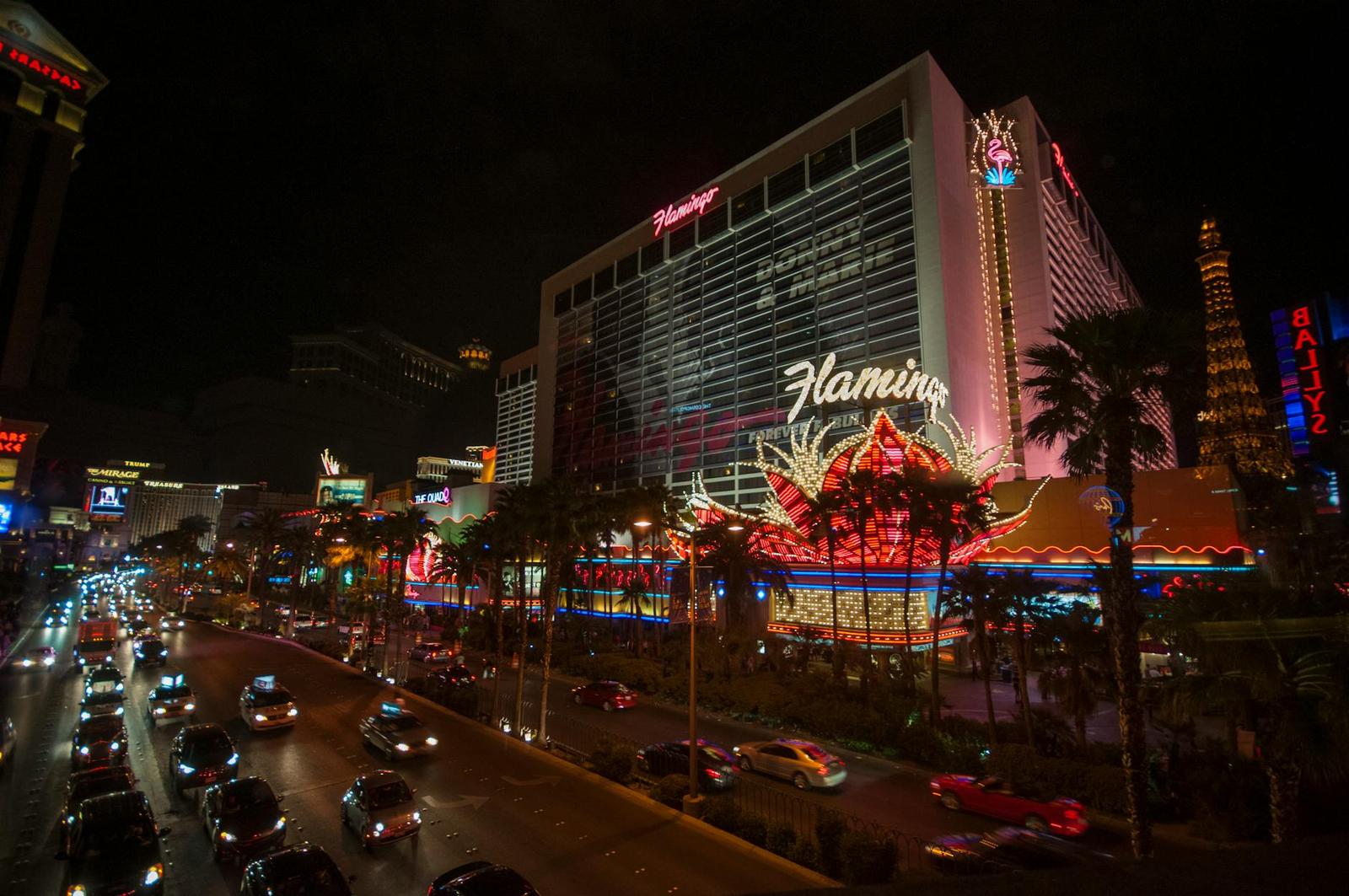 A neon-lit casino resort tower glowing above a busy street at night