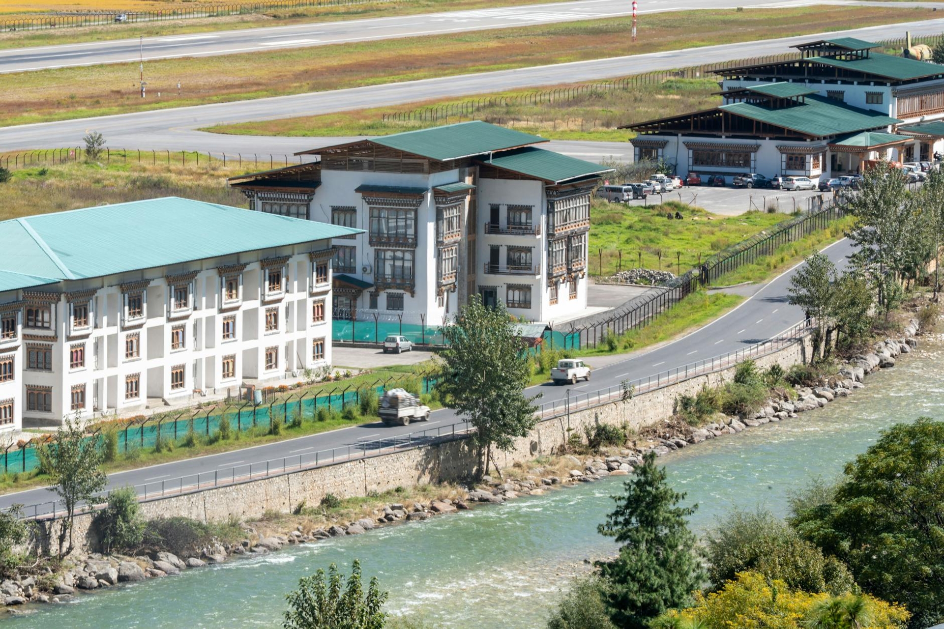 An airport terminal with traditional carved roofs beside a mountain river