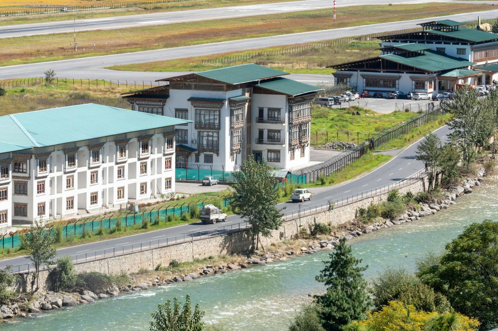 An airport terminal with traditional carved roofs beside a mountain river