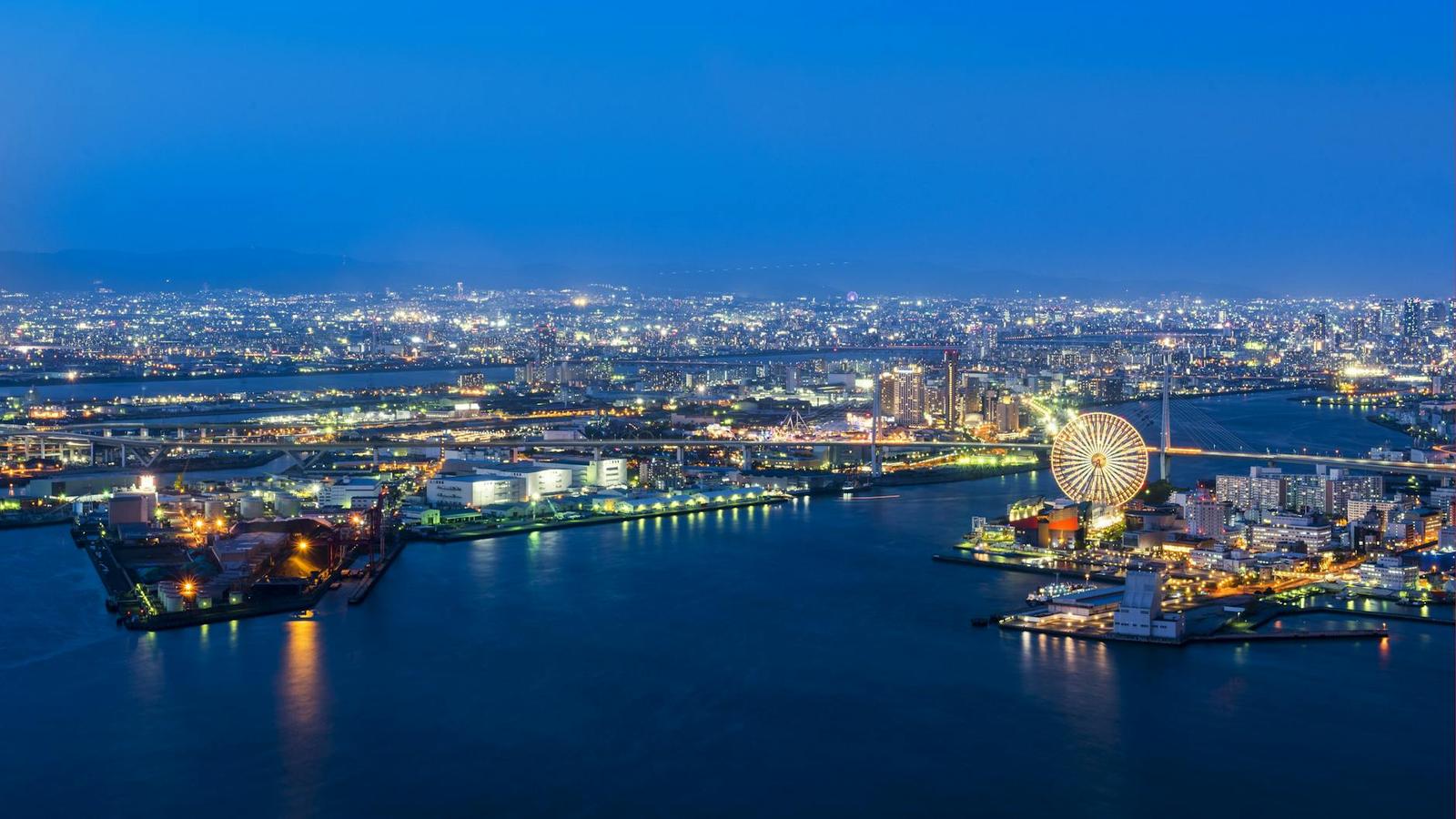 Aerial night view of a harbour city with a lit ferris wheel by the water