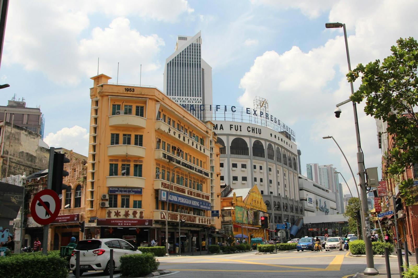 A historic yellow corner building on a busy city street with traffic