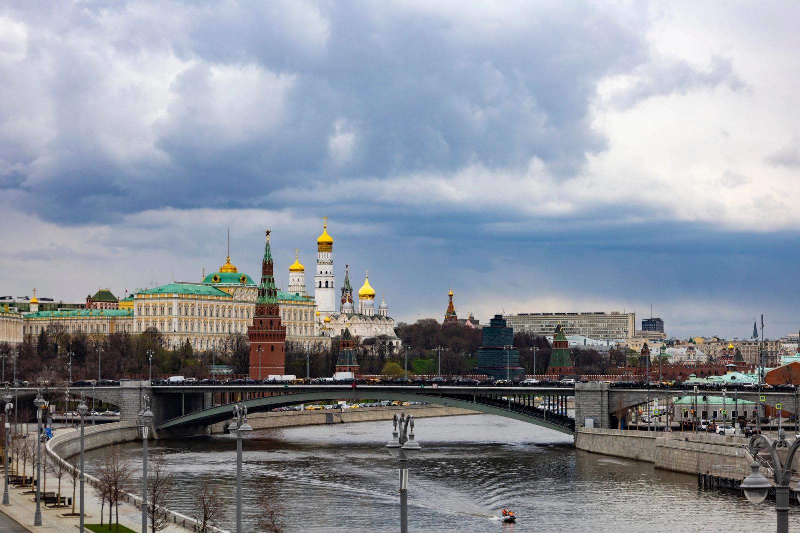 A picturesque view of the Moscow Kremlin with a bridge over the Moskva River under a dramatic sky