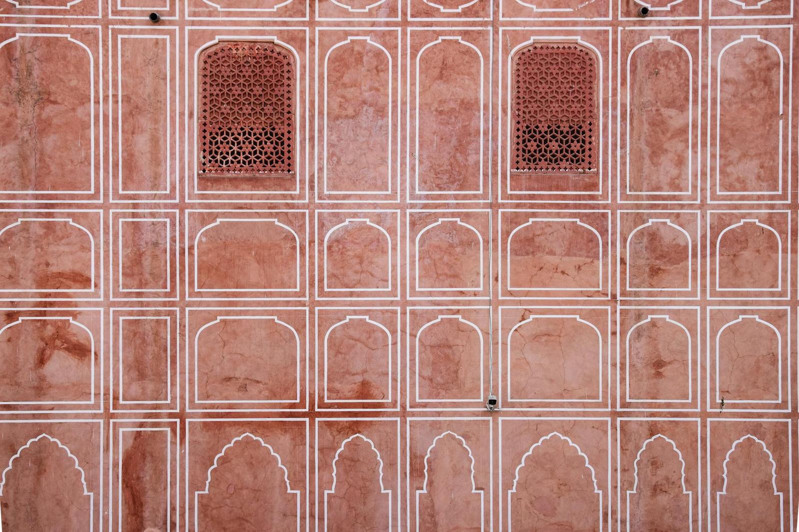 A close-up of latticed sandstone windows in a repeating arched pattern