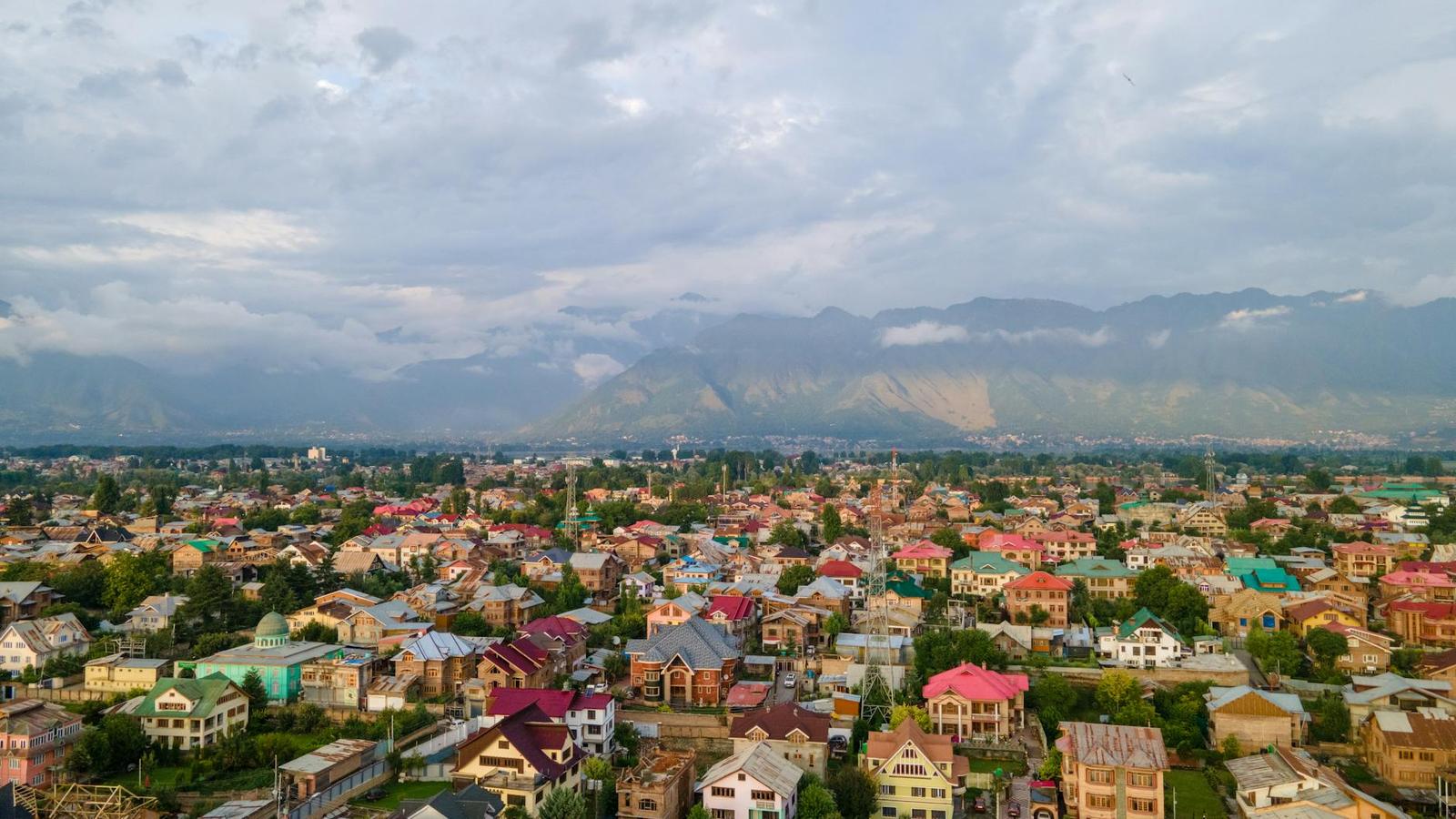Aerial view of a colourful hillside town beneath a mountain range