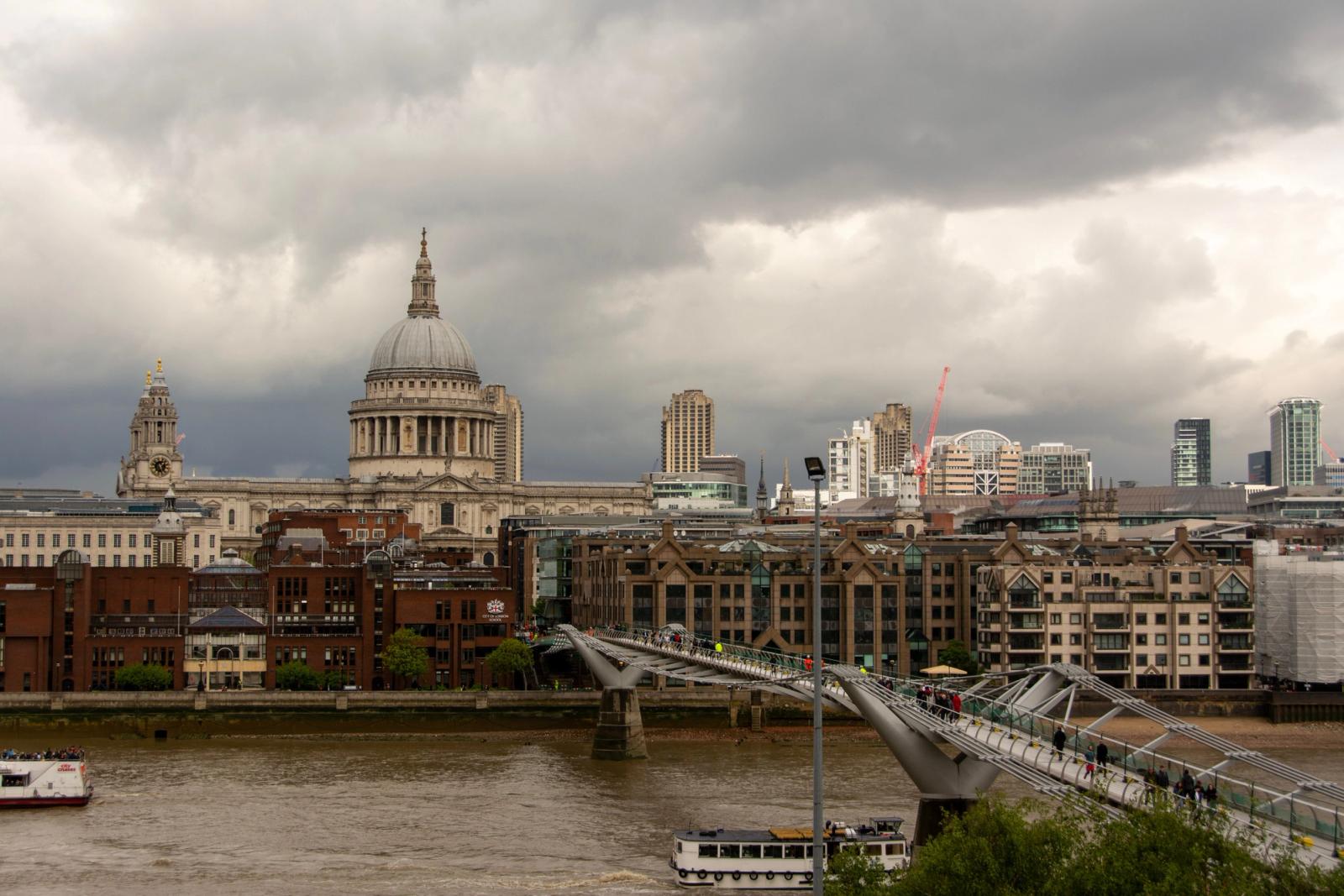 View of St Paul's Cathedral and Millennium Bridge over Thames with cloudy sky in London