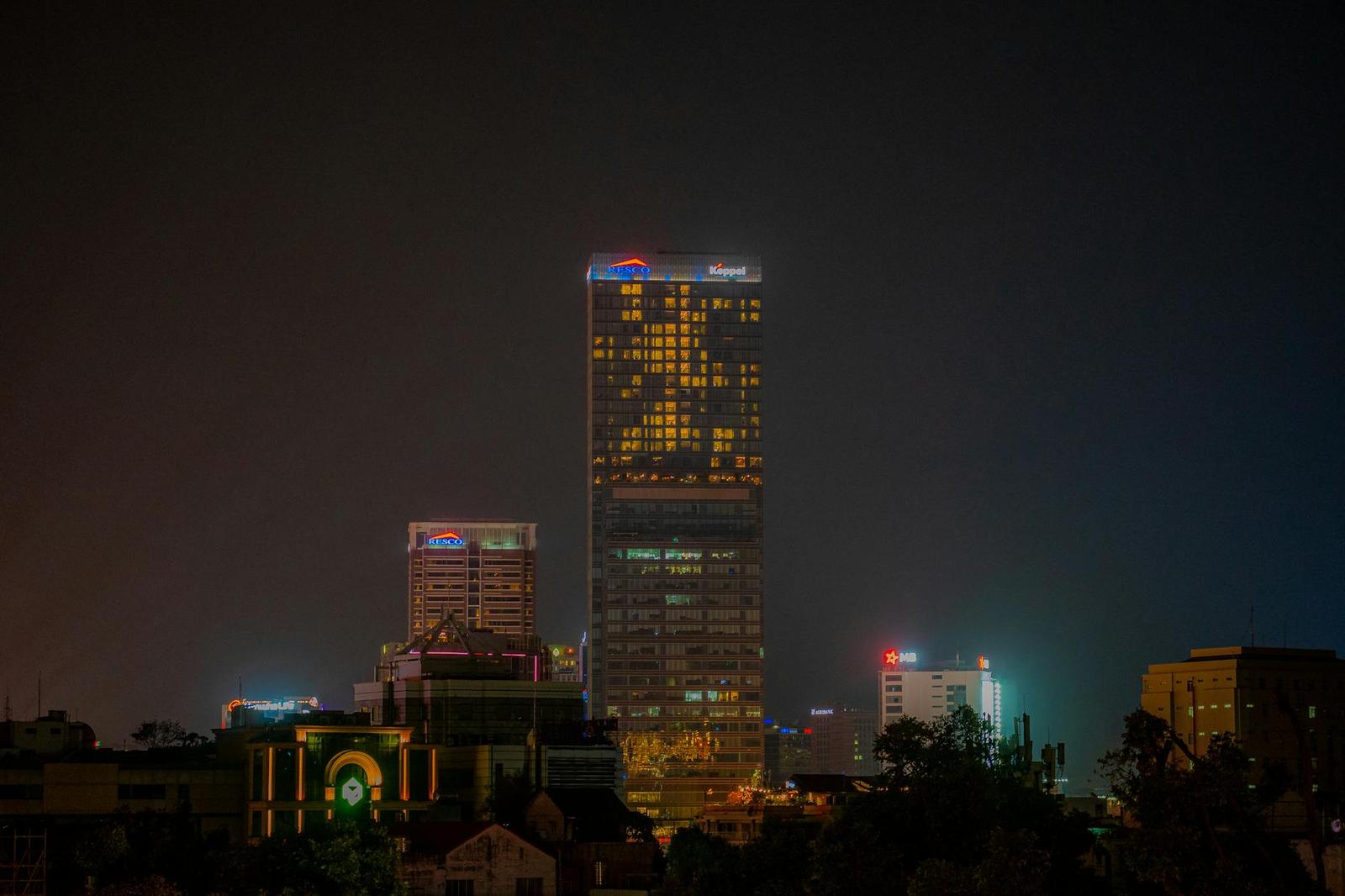 A lit high-rise tower standing above a dark city skyline at night