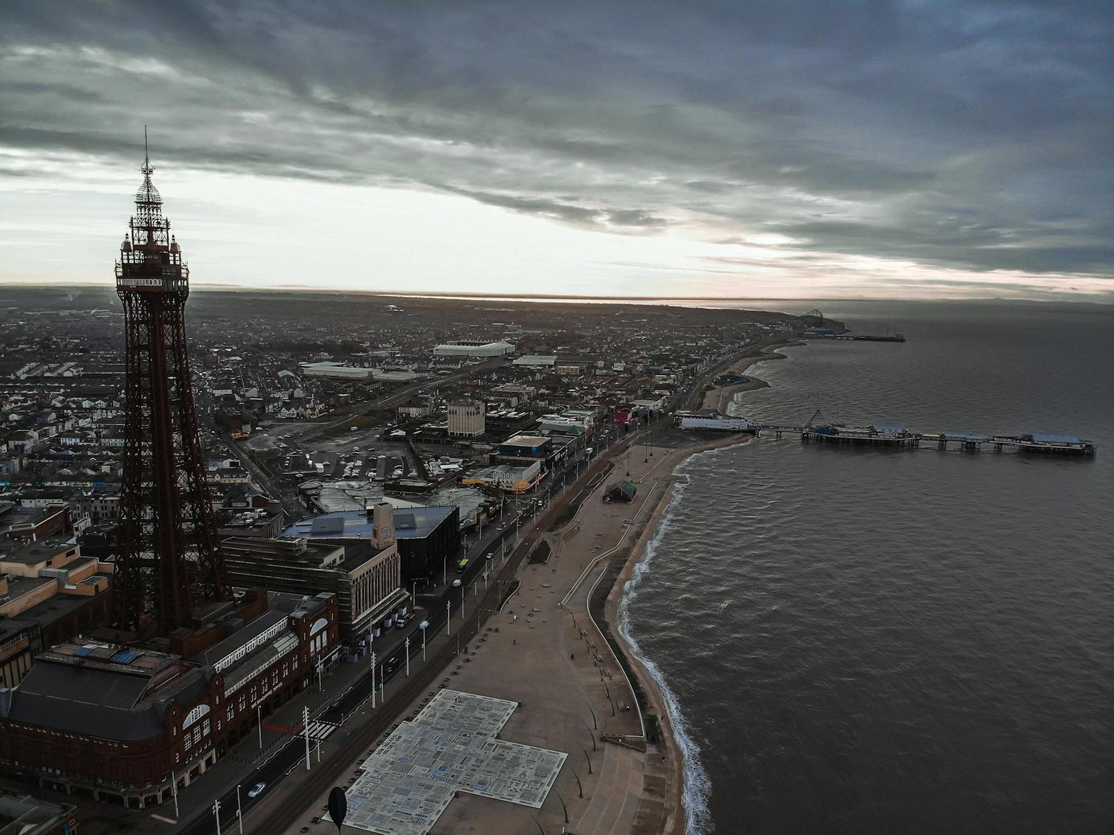 A tall lattice tower overlooking a seaside promenade and pier at dusk