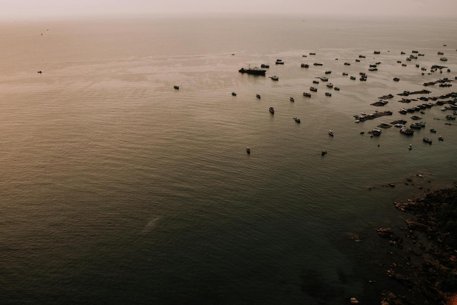 Scattered fishing boats dotting a calm sea at dusk