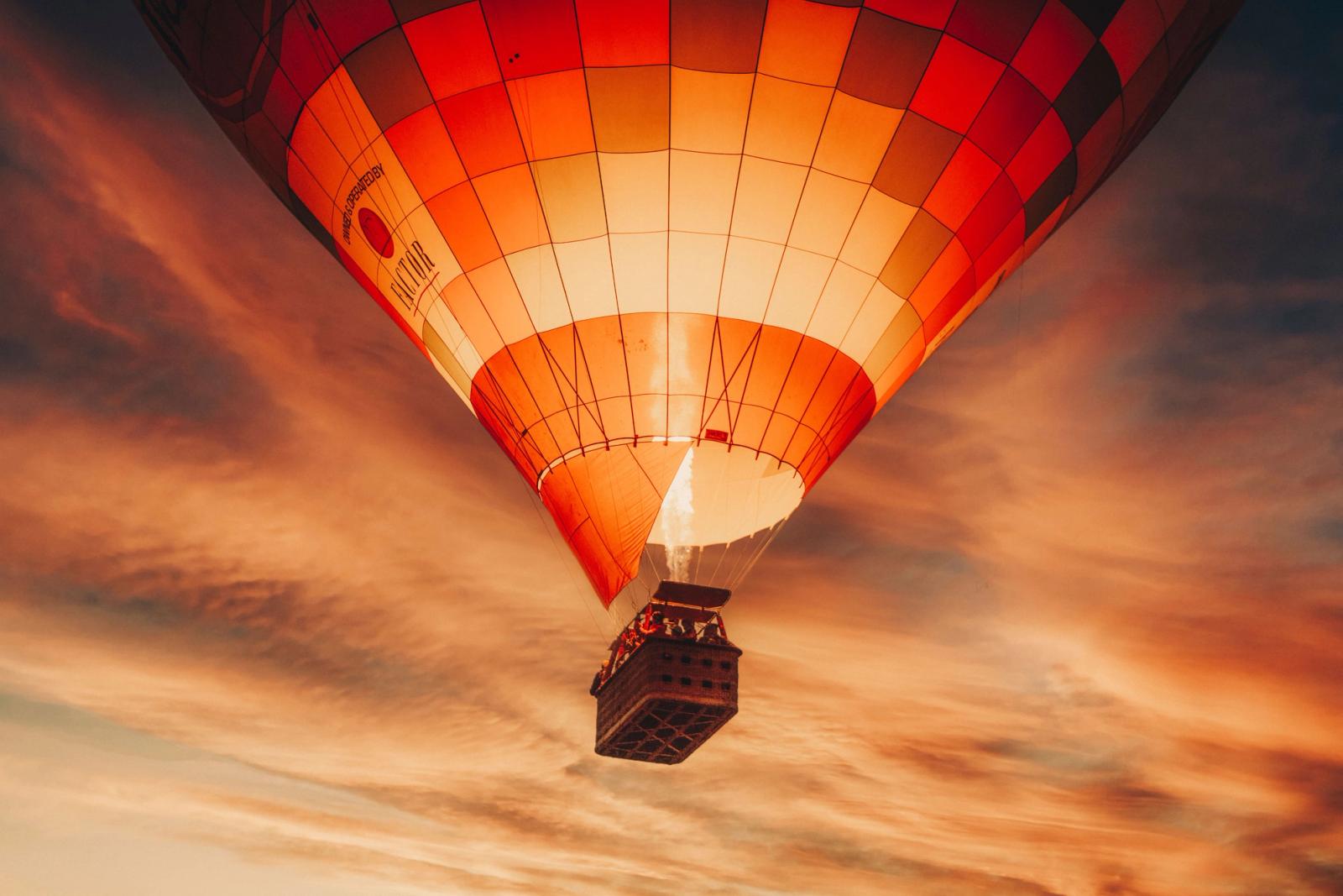 A vibrant hot air balloon floats against a dramatic sunset sky in Pushkar, India, capturing the essence of adventure and freedom