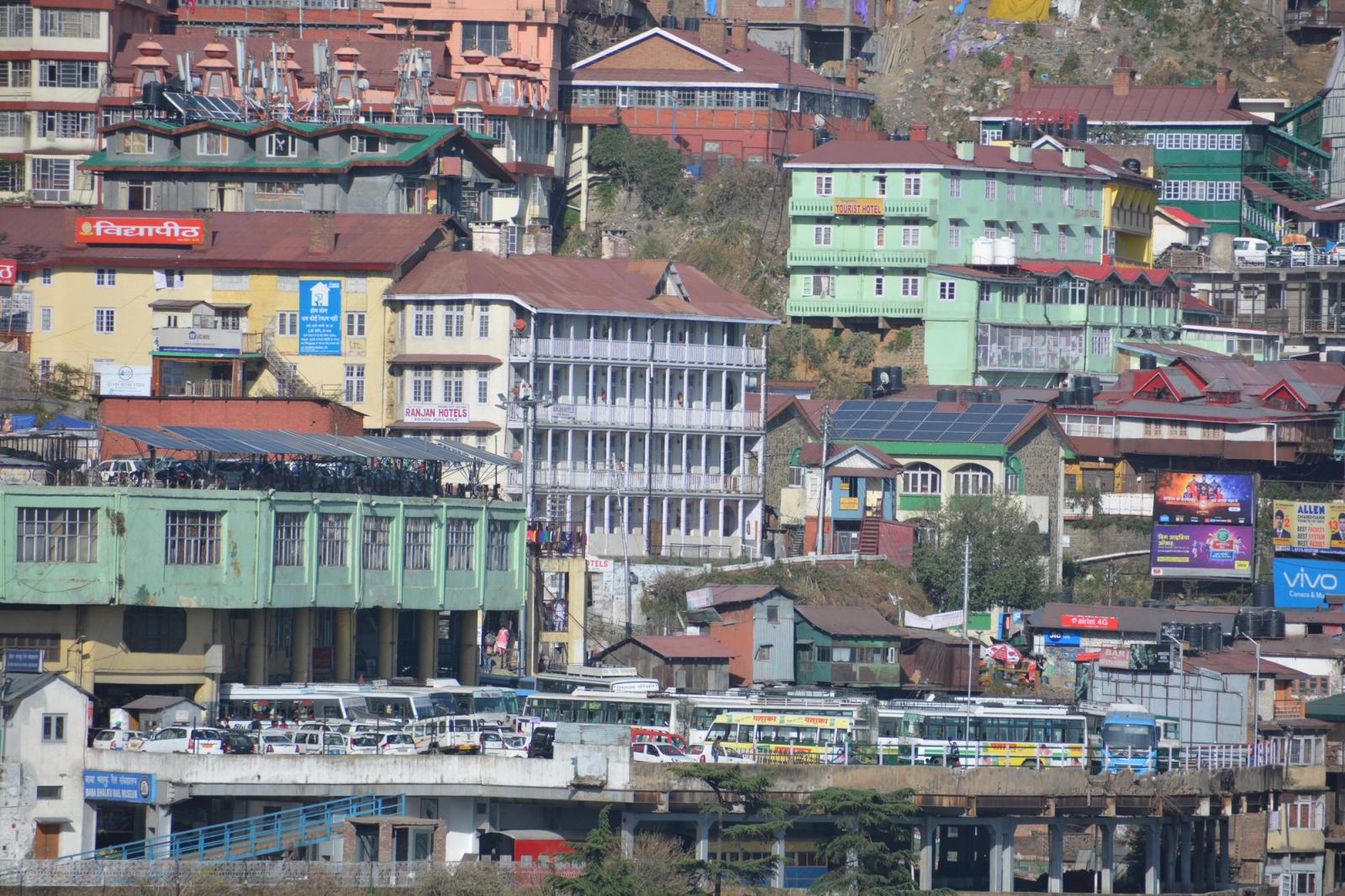 Colourful multistorey buildings clustered on a steep hillside above a bus terminal