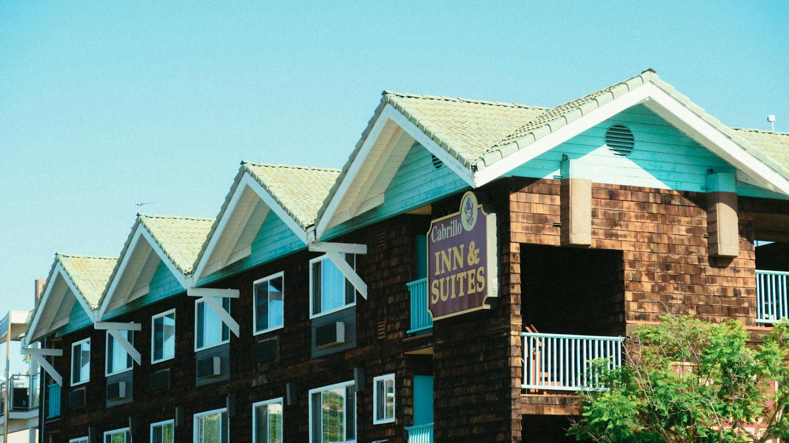 A row of gabled roofs on a roadside inn under a clear blue sky