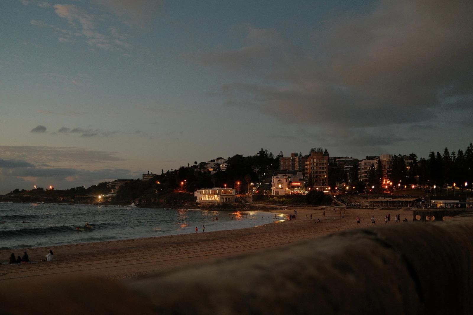 Evening view of a beachfront cityscape in Sydney, Australia with twinkling lights