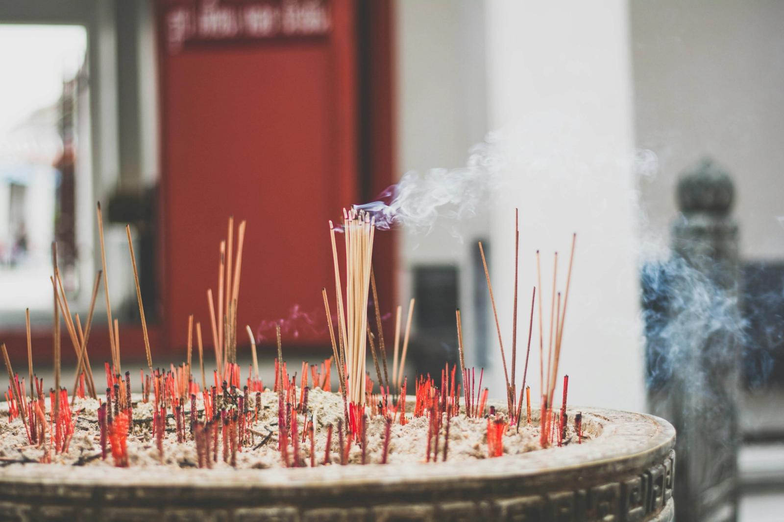 Incense sticks smoulder in a large urn outside a temple entrance
