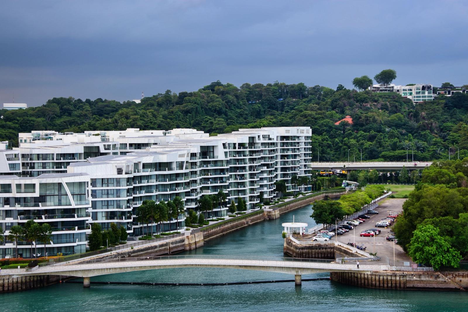 Aerial view of contemporary buildings by the water in Singapore with lush greenery in the background