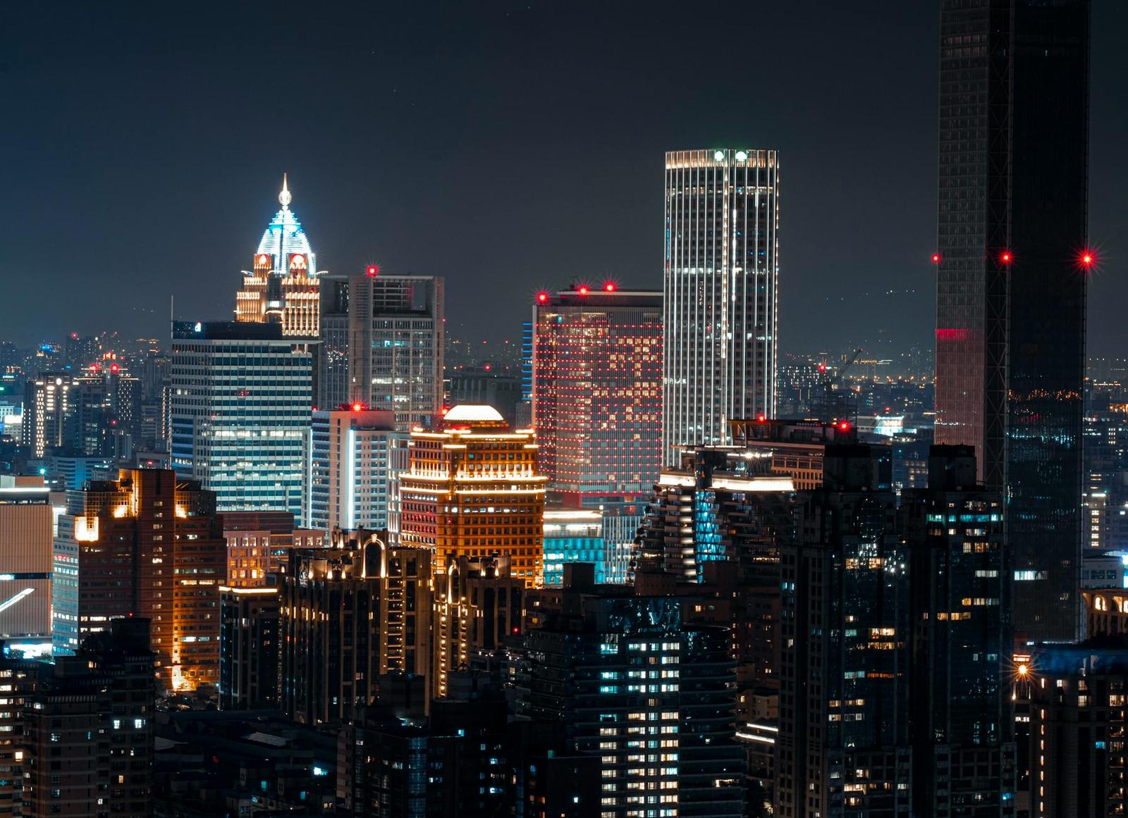 An illuminated city skyline crowded with skyscrapers against a dark night sky